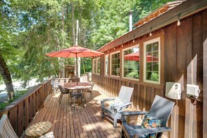 A wooden deck with outdoor furniture, including a table and chairs, and a red umbrella.