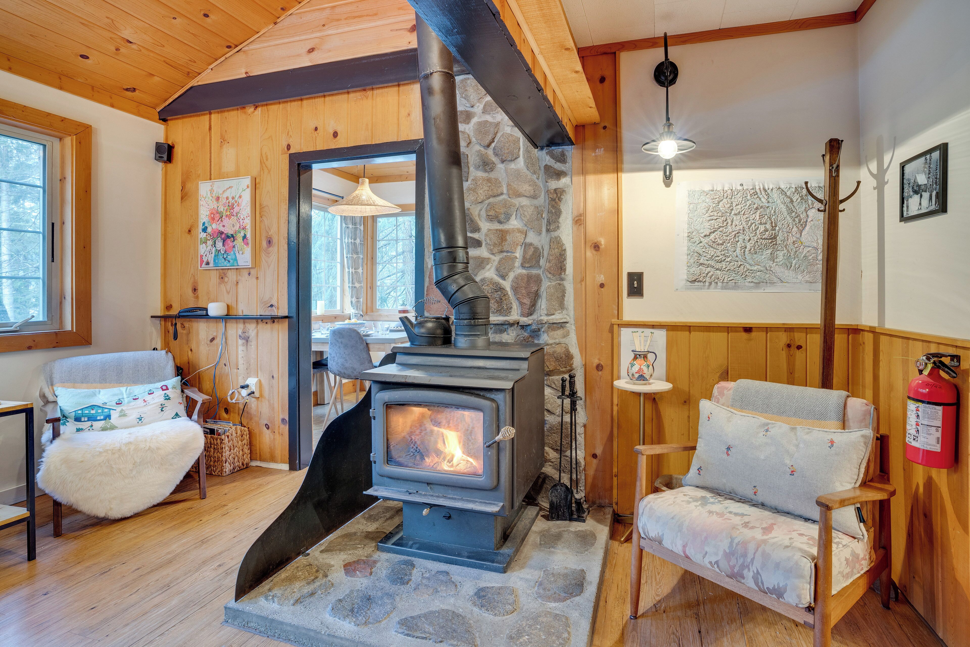 A cozy cabin interior with a stone fireplace, wooden walls, and a comfortable seating area.