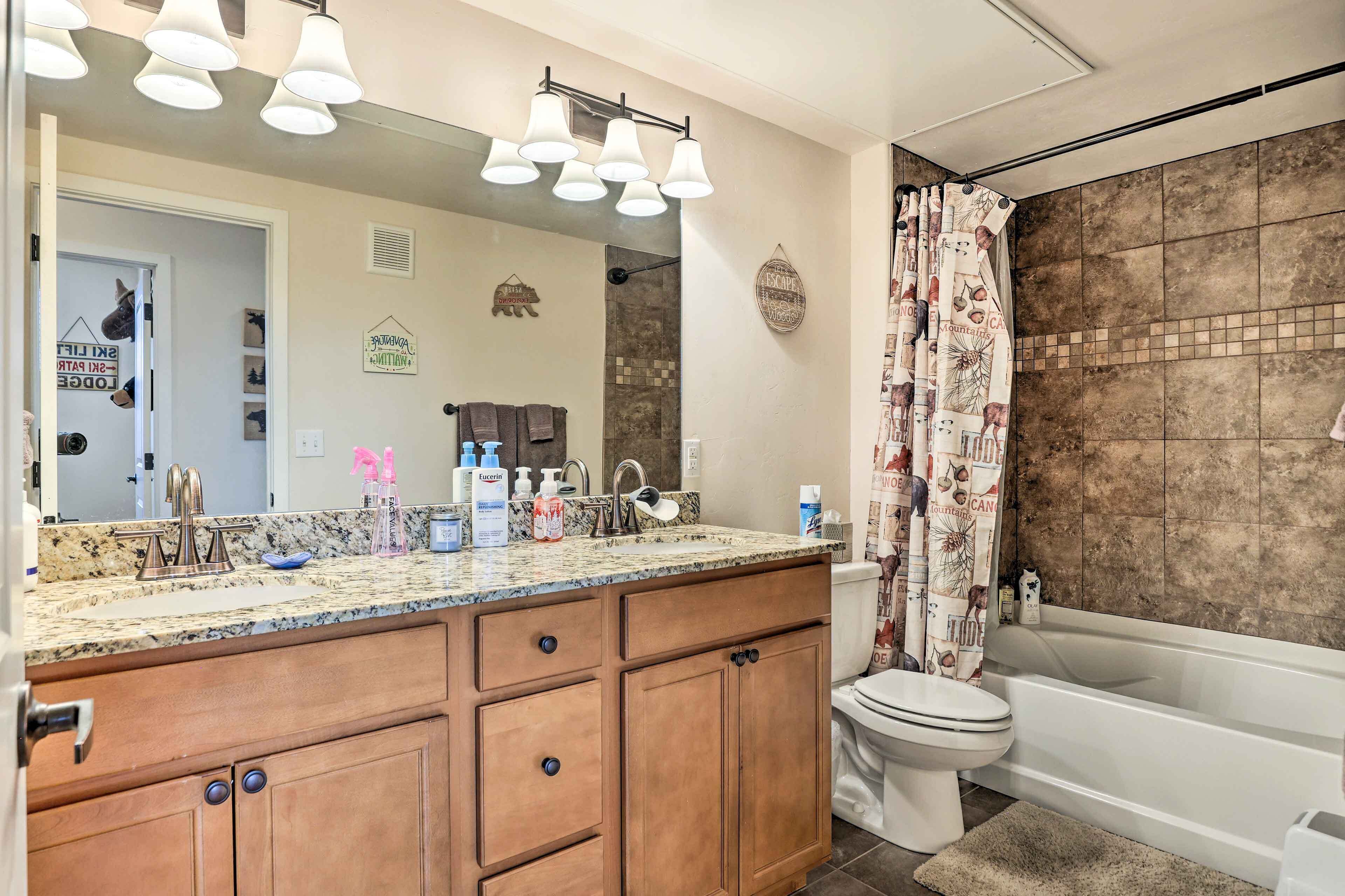 A bathroom with a large mirror, vanity, sink, and bathtub.