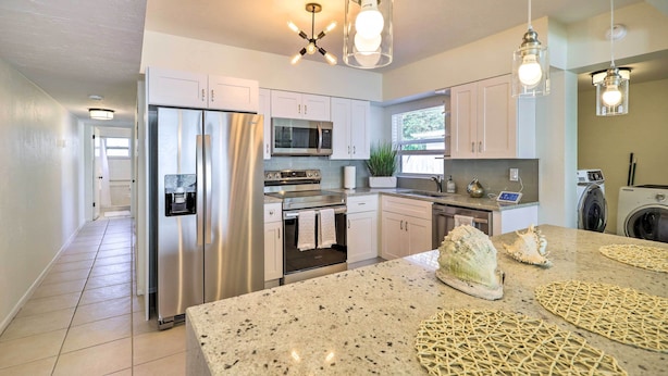 A modern kitchen with stainless steel appliances, a granite countertop, and pendant lighting.