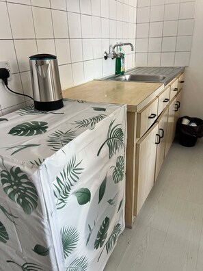 Eine Küche mit Arbeitsplatte, Spüle, Schränken und einem Mülleimer.