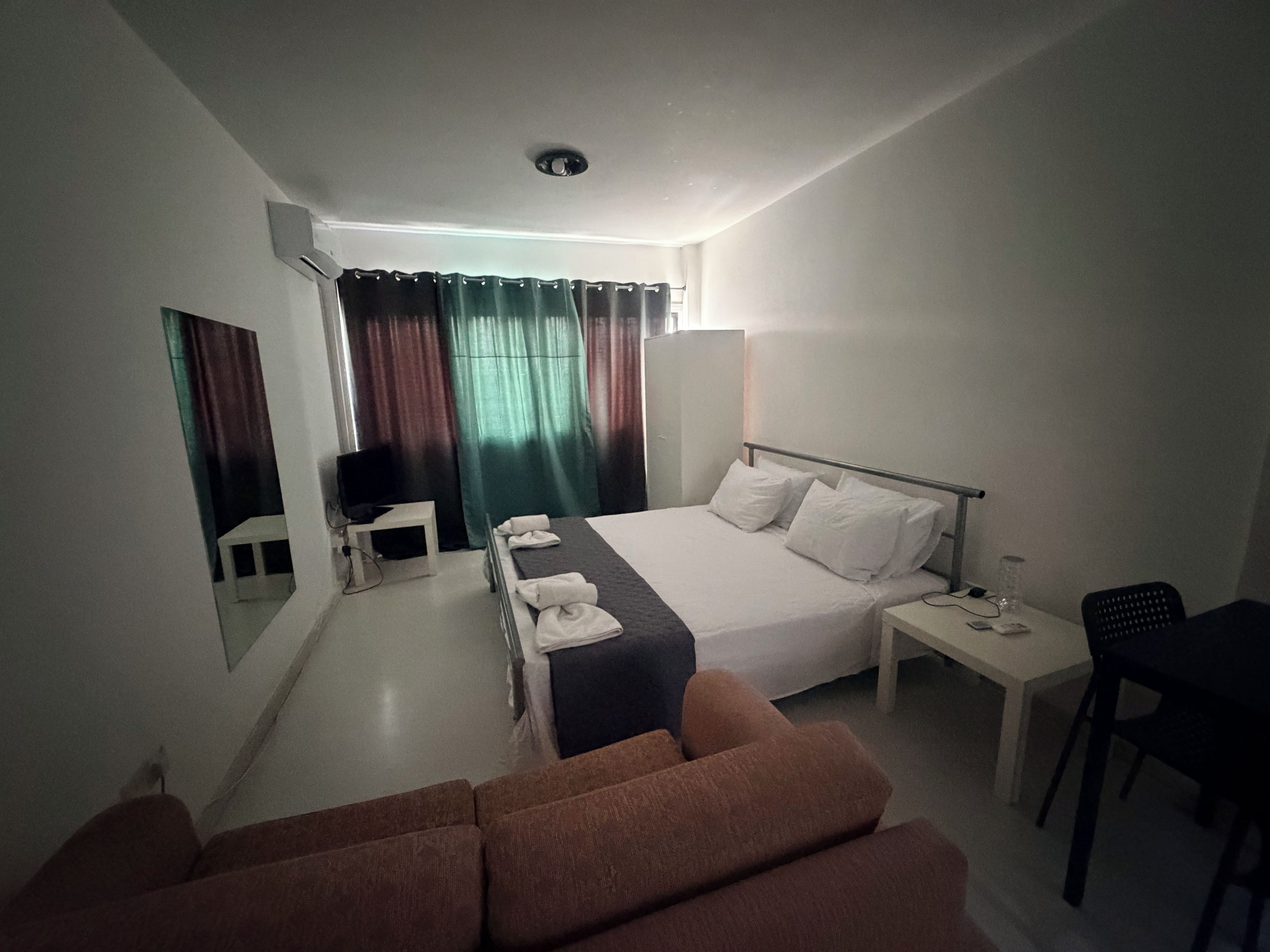 Una habitación de hotel con cama, escritorio, silla, televisor y sofá.