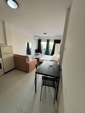 Une chambre d’hôtel compacte comprenant un coin cuisine, un lit, une table à manger avec des chaises et un canapé.