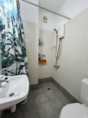 A bathroom with a shower, a sink, and a toilet.