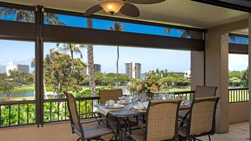 A dining area with a table set for four, overlooking a scenic view of a golf course and buildings.