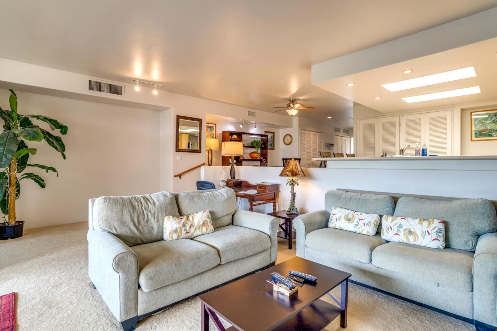 A living room with two sofas, a coffee table, and a dining area with a table and chairs.