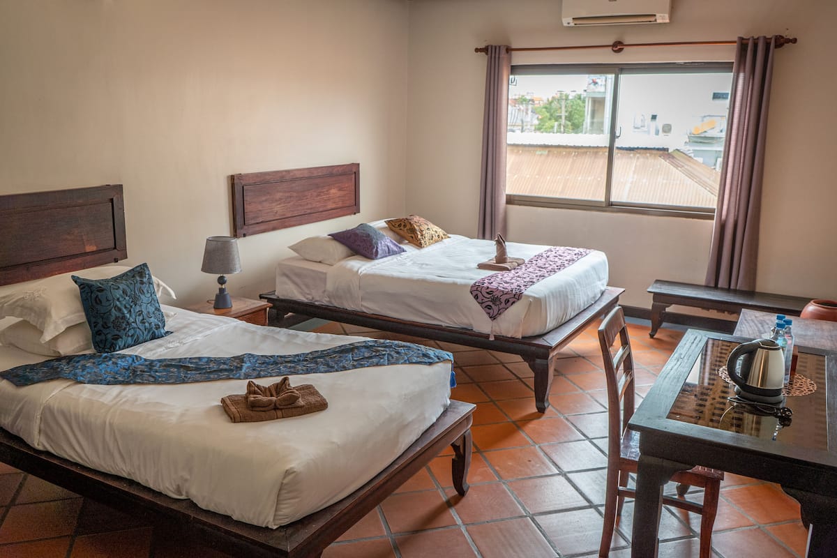 Een hotelkamer met twee bedden, een tafel en een raam met gordijnen.