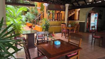A restaurant with wooden furniture, a glass table, and a staircase leading to an upper level.