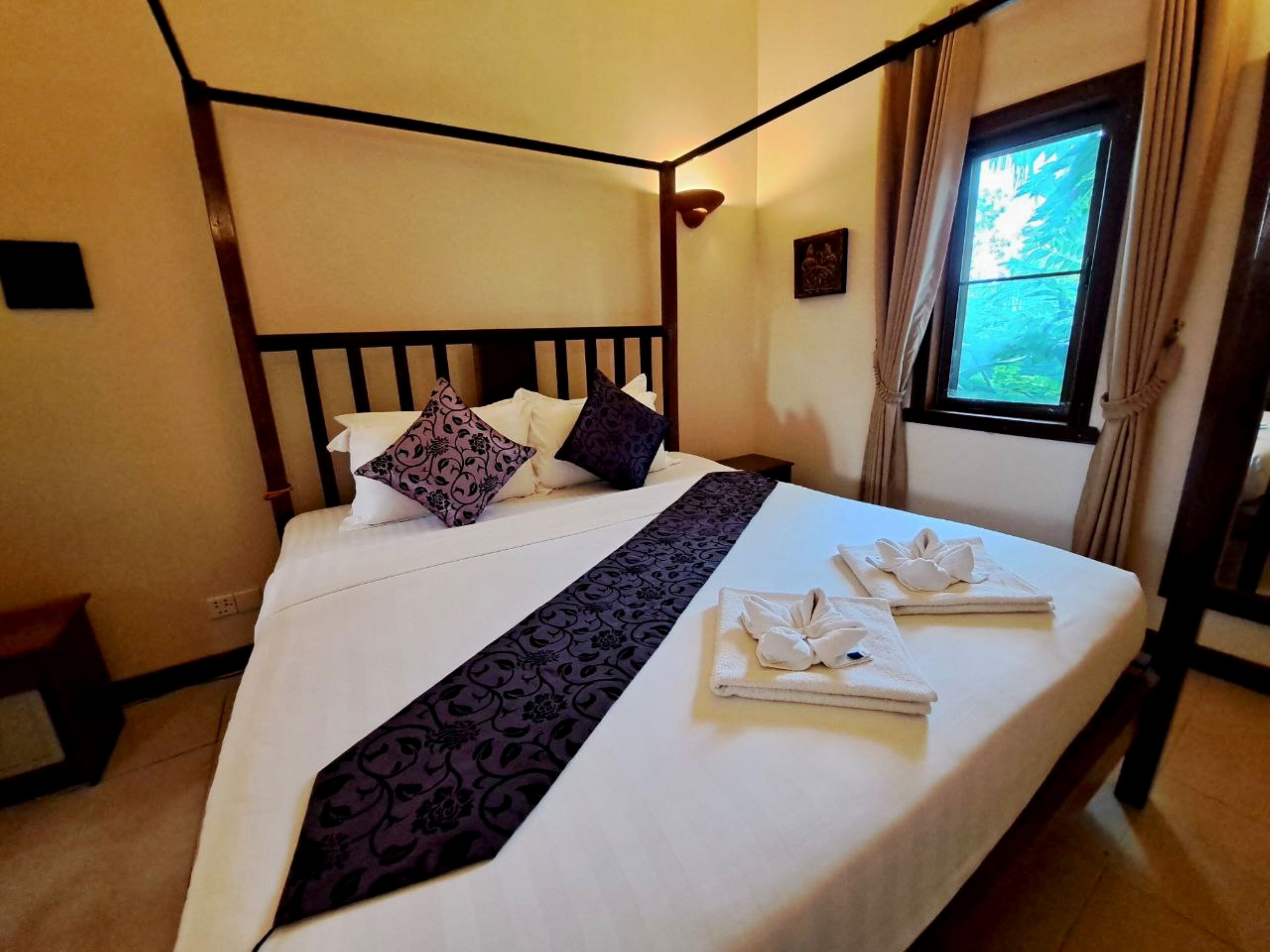 Una cama bien hecha con un corredor de cama blanco y negro, dos almohadas y dos toallas dobladas sobre la cama.