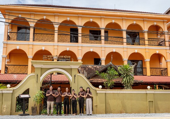 A building with multiple arches and balconies, a sign indicating a hotel, and a group of people standing in front. - DEN HOTEL TOTONOU SIEM REAP (Siem Reap)