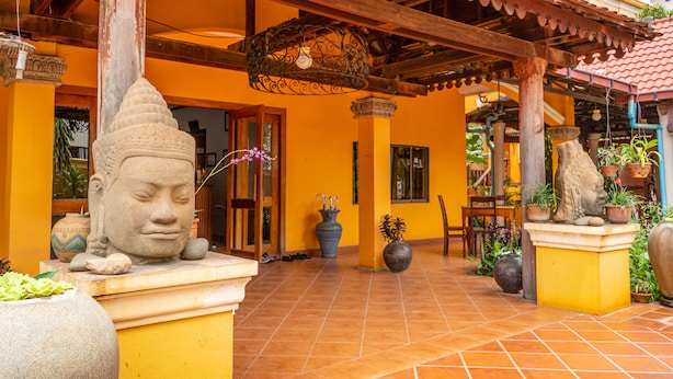 Une cour avec une statue de Bouddha, des plantes en pot et un sol carrelé.