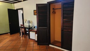 Un couloir avec un sol carrelé, un bureau avec une lampe, une chaise et un réfrigérateur.
