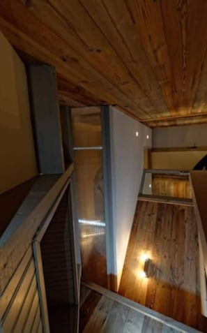 Interior em madeira com escadaria e um pequeno espaço de estar.