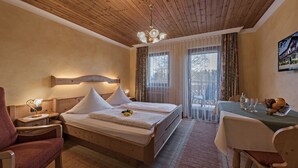 A hotel room with a wooden ceiling, a bed with white bedding, a desk with a table, and a chair. - Ferienwohnung, 80m², 2 Schlafzimmer, Balkon Bzw. Terrasse (Eggstätt)