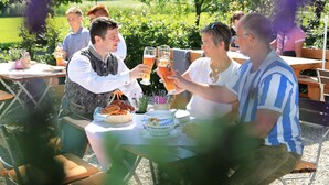A group of people toasting with drinks at an outdoor table with a basket of food and a bottle of beer. - Ferienwohnung, 80m², 2 Schlafzimmer, Balkon Bzw. Terrasse (Eggstätt)