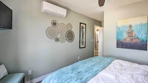 A bedroom with a bed, a wall-mounted air conditioner, decorative wall art, and a ceiling fan. - Dog-friendly San Diego Home - 1 Mi to Ocean Beach (San Diego)
