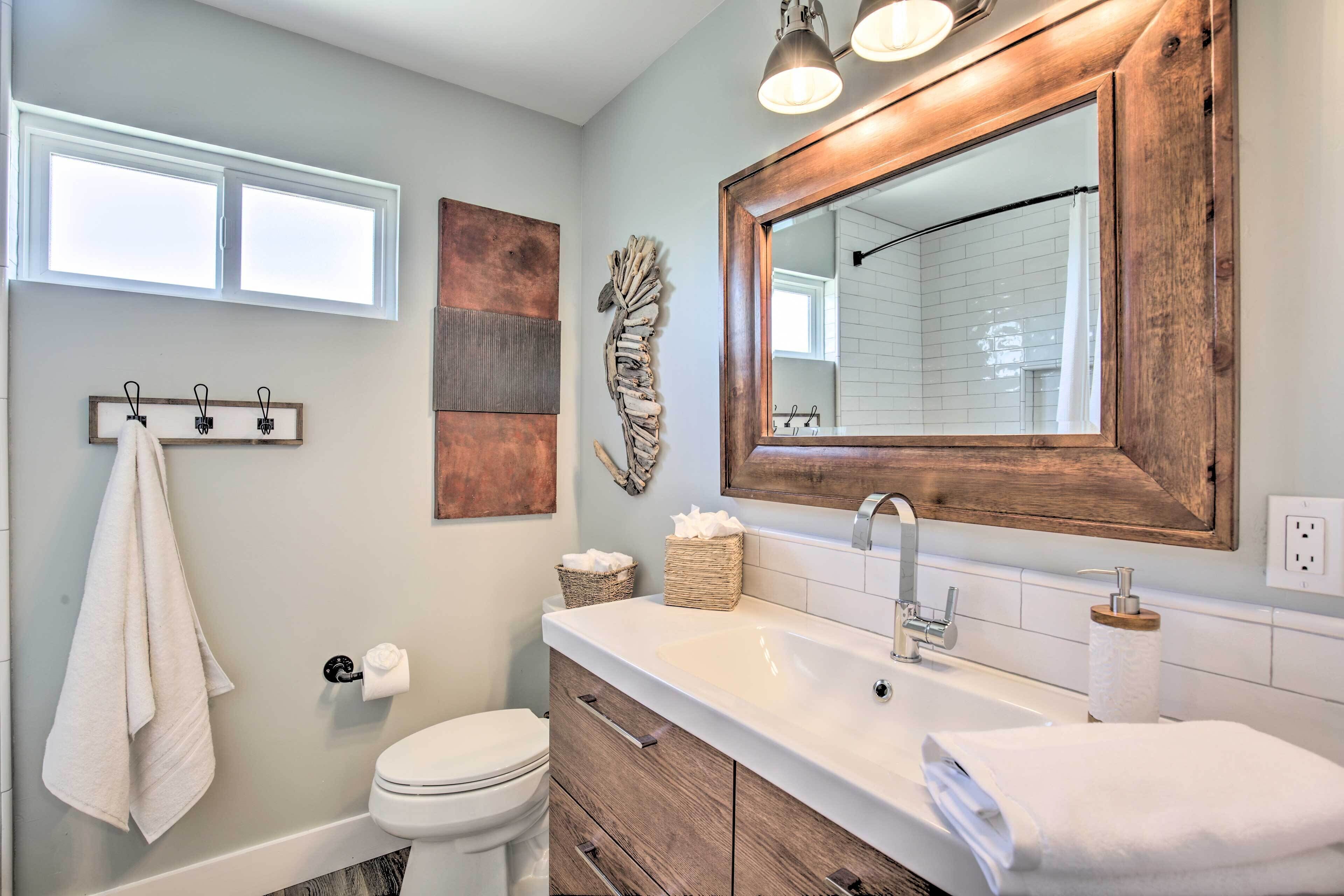 A bathroom with a white sink, wooden vanity, a large mirror, and a towel rack.