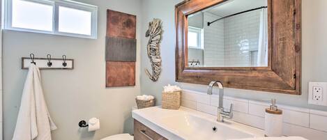 A bathroom with a white sink, wooden vanity, a large mirror, and a towel rack.