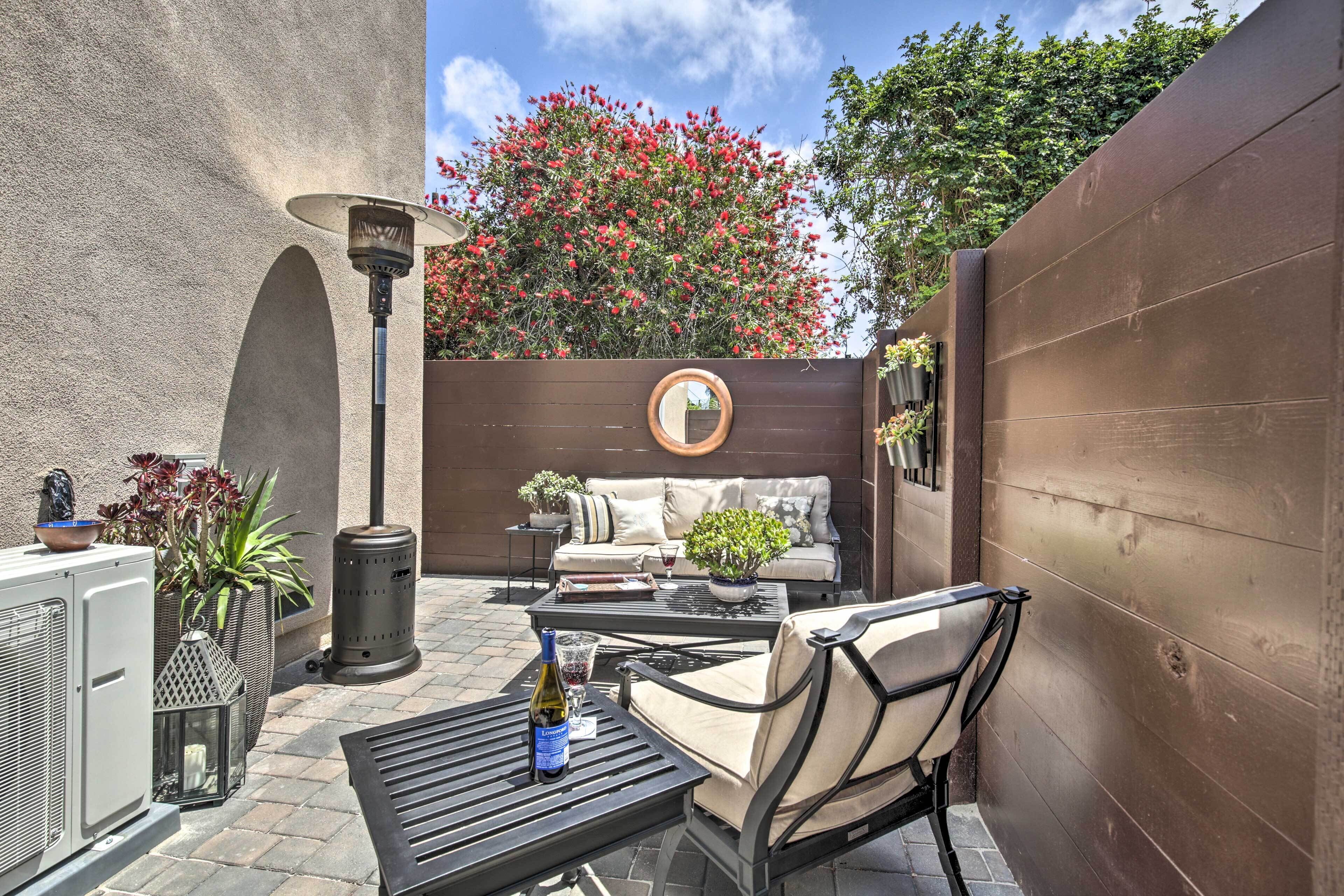 Une terrasse avec un canapé, des chaises, une table et un miroir décoratif.