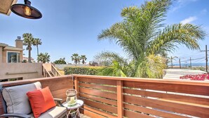 A wooden deck with a cushioned bench and a small table, overlooking a landscaped area with palm trees and a view of the ocean. - Dog-friendly San Diego Home - 1 Mi to Ocean Beach (San Diego)