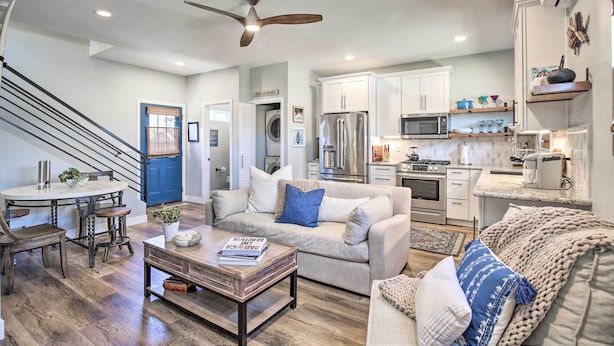 A spacious living room with a sofa, coffee table, and a dining area with chairs. A kitchen with modern appliances is visible in the background. - Dog-friendly San Diego Home - 1 Mi to Ocean Beach (San Diego)