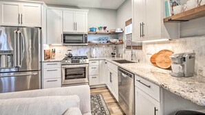 A modern kitchen with stainless steel appliances, white cabinetry, and a marble countertop. - Dog-friendly San Diego Home - 1 Mi to Ocean Beach (San Diego)
