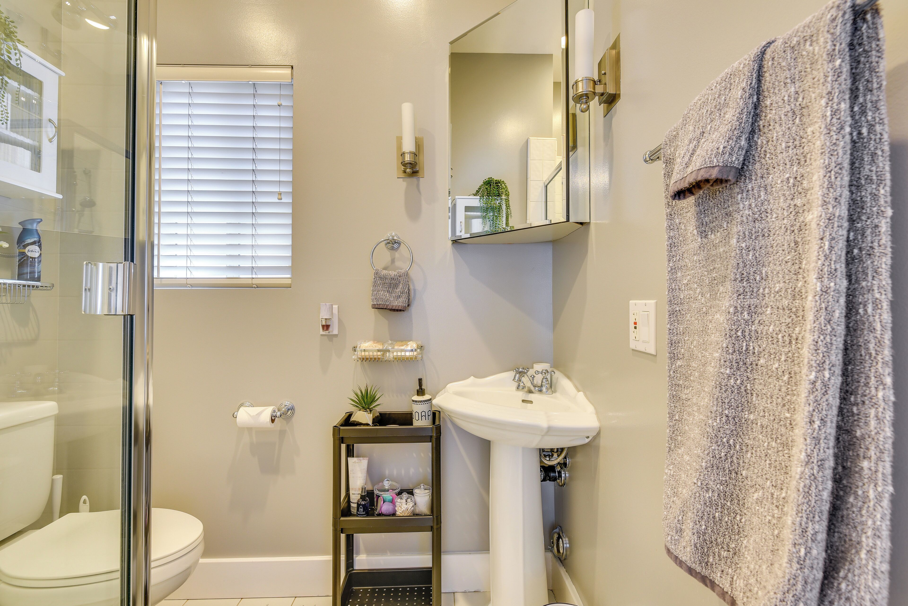 A bathroom with a glass shower enclosure, a white sink, and a towel rack.