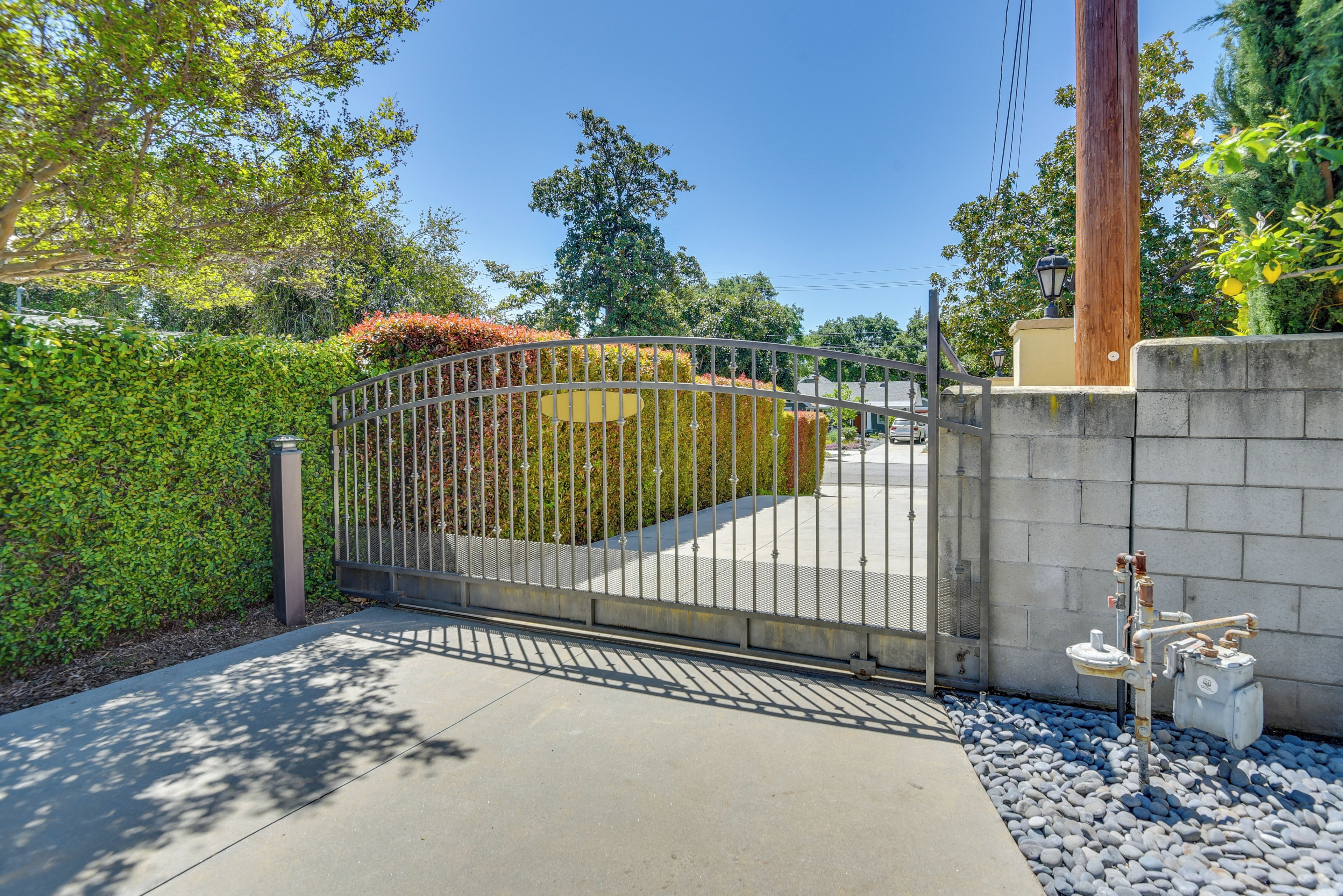 A gated entrance with a metal fence, a concrete wall, and a utility box.