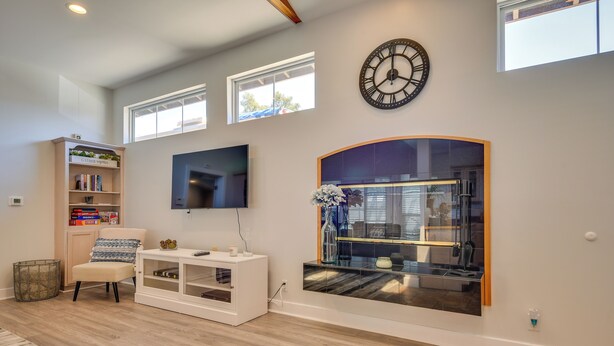 A living room with a TV, bookshelf, and a large clock on the wall. - Luxe Pasadena Casita w/ Fireplace & Grill (Pasadena)