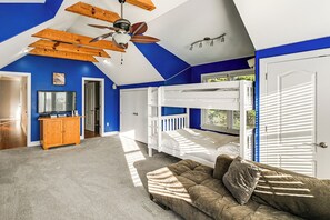 A bedroom with a bunk bed, a sofa, a wooden cabinet, and a ceiling fan. - Walk to Beach! Group-friendly Ocean City Getaway (Ocean City)