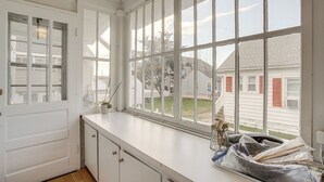 A kitchen with white cabinets, a large window with multiple panes, and a view of neighboring houses. - Near Beach & Boardwalk! Group Escape in Ocean City (Ocean City)