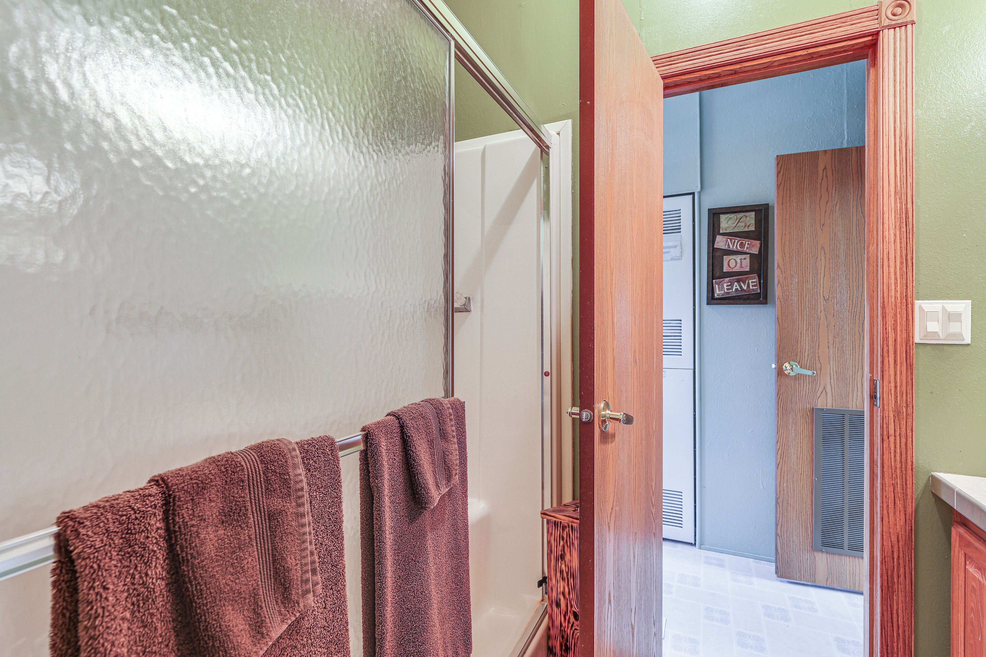 Une salle de bain avec une douche à parois de verre, une porte en bois et un porte-serviettes avec deux serviettes.