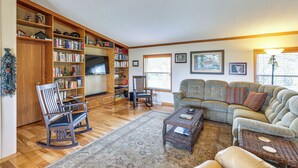 A living room with a sectional sofa, a rocking chair, a coffee table, and a bookshelf. - Hermosa Home w/ Deck: 2 Mi to Custer State Park! (Hermosa)