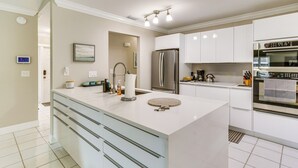 A modern kitchen with white cabinetry, a large island, stainless steel appliances, and a pendant light fixture. - Wellington Vacation Rental: Private Saltwater Pool (Wellington)
