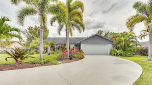 A residential driveway leading to a garage, surrounded by palm trees and various plants. - Wellington Vacation Rental: Private Saltwater Pool (Wellington)