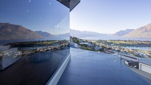 Vista panorámica desde un balcón en un rascacielos, con vistas a un lago y montañas.