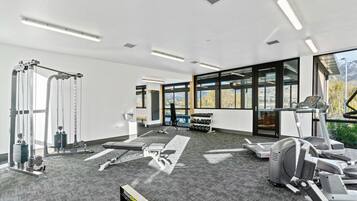A modern gym with cardio equipment, weight machines, and a large window offering a mountain view.
