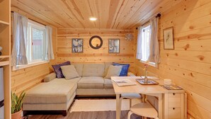 A cozy cabin interior with a sofa, a small table, and a desk. - Modern Lynnwood Tiny House: 16 Mi to Seattle! (Lynnwood)