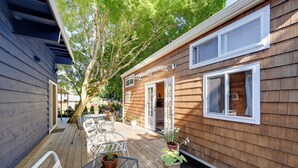 A wooden house with a covered patio, outdoor seating, and potted plants. - Modern Lynnwood Tiny House: 16 Mi to Seattle! (Lynnwood)