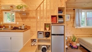 A wooden cabin interior with a kitchen, a dining area, and a bedroom. - Modern Lynnwood Tiny House: 16 Mi to Seattle! (Lynnwood)