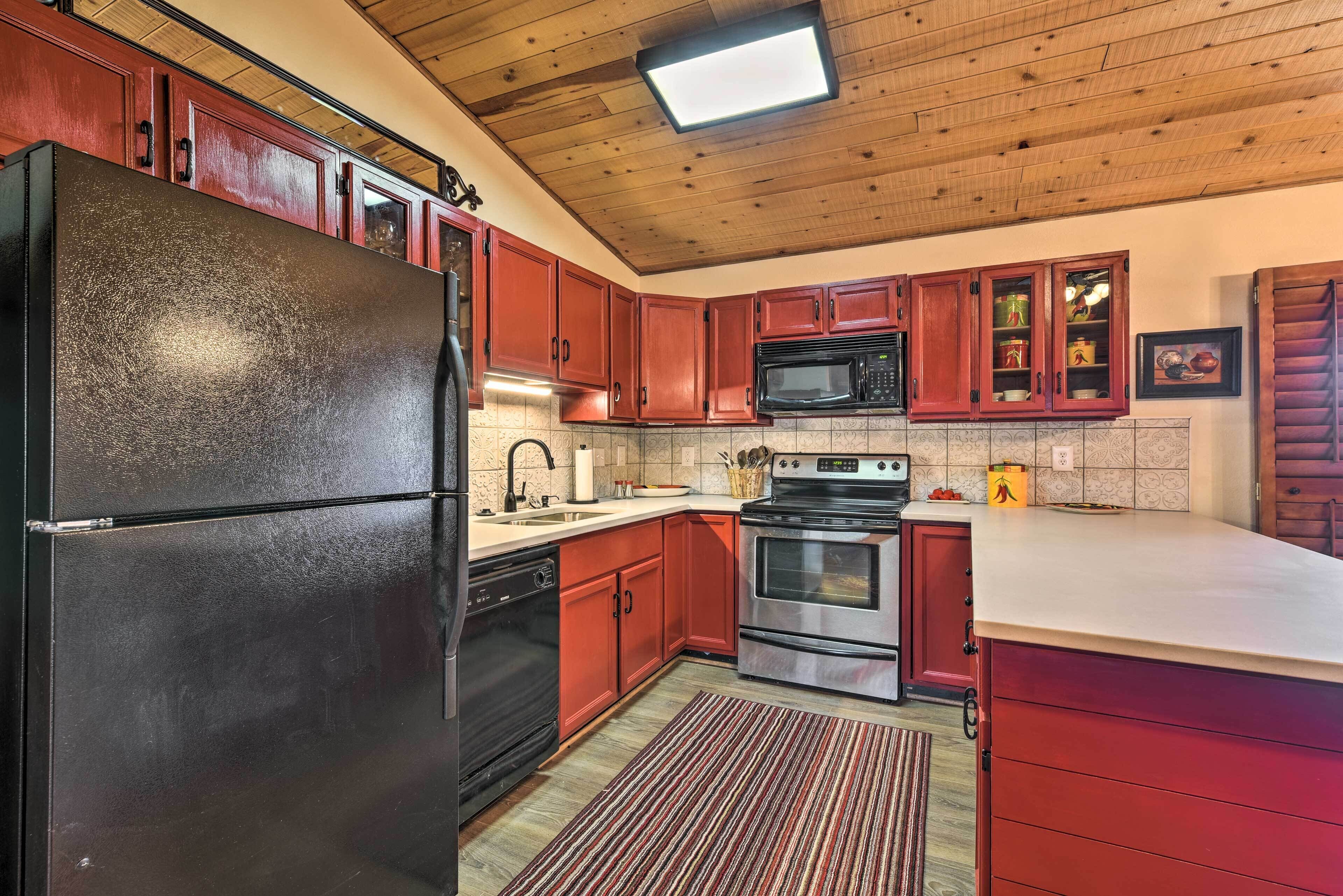 A kitchen with wooden cabinets, a stainless steel refrigerator, a microwave, and an oven.