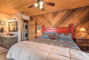 Ein Schlafzimmer mit Holzboden, einem Bett mit gemusterten Betttextilien, einer Waschmaschine und einer kleinen Küchenzeile.