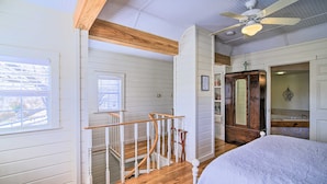 A room with a wooden staircase, a bed, a ceiling fan, and a view of the outdoors. - Large Groups,walk to Main,fireplaces, Jacuzzi Tubs (Fredericksburg)