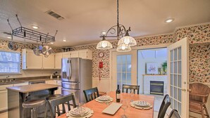 A kitchen with a bar area, a dining table set for six, and a fireplace in the background. - Walk to Main St: Multiple Fireplaces, Jacuzzi Tubs (Fredericksburg)