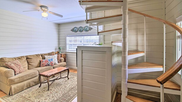 A living room with a sofa, coffee table, and a spiral staircase. - Walk to Main St: Multiple Fireplaces, Jacuzzi Tubs (Fredericksburg)