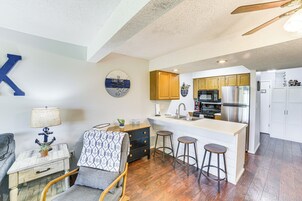 A compact kitchen with a central island, wooden cabinets, and a bar stool arrangement.