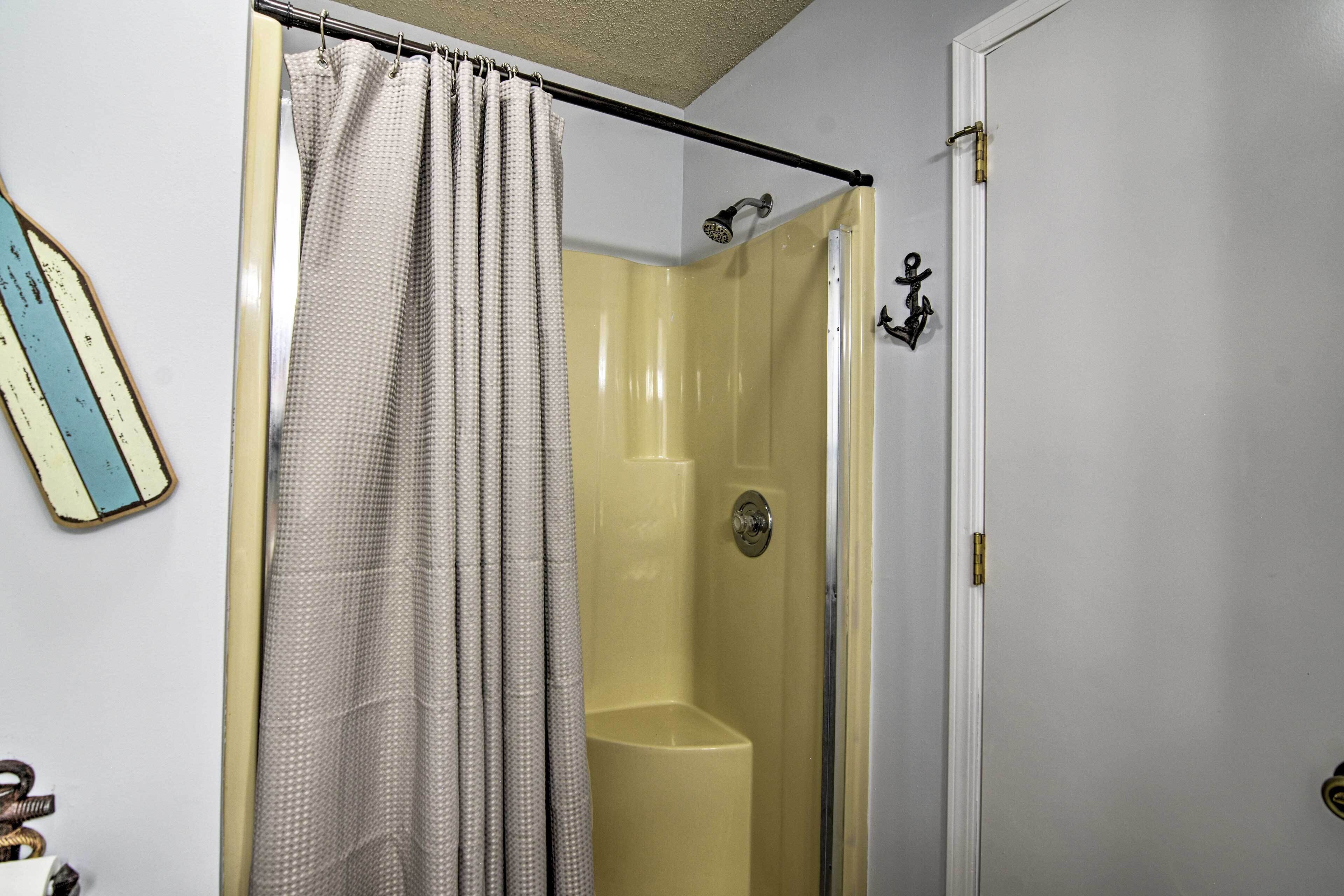 A bathroom with a shower, a toilet, and a door with a lock.