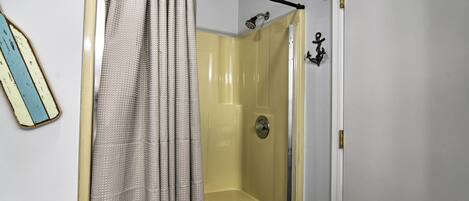 A bathroom with a shower, a toilet, and a door with a lock.