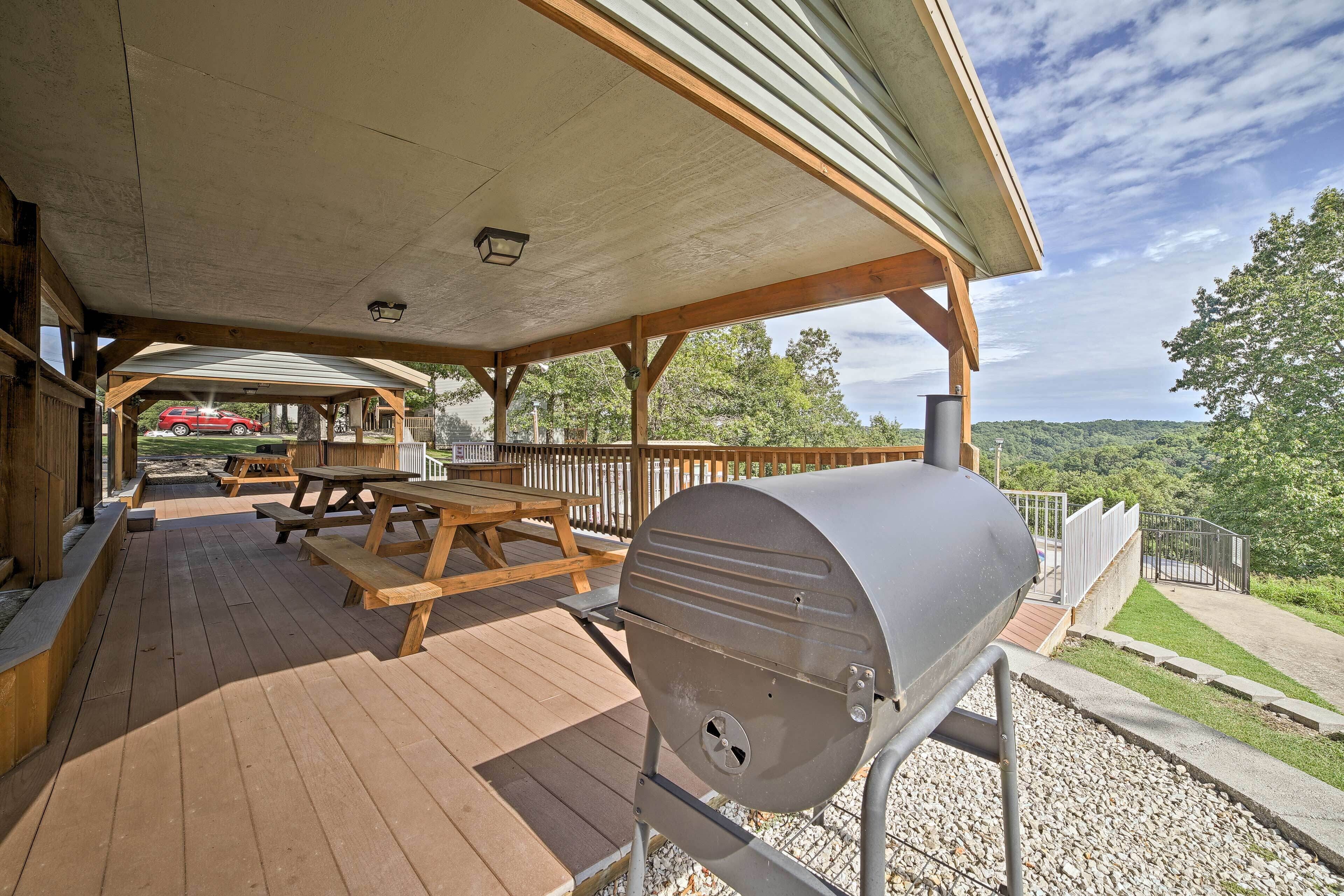 A covered outdoor area with picnic tables and a barbecue grill.