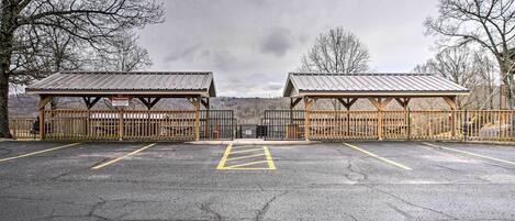 A parking lot with two covered shelters and a fence.